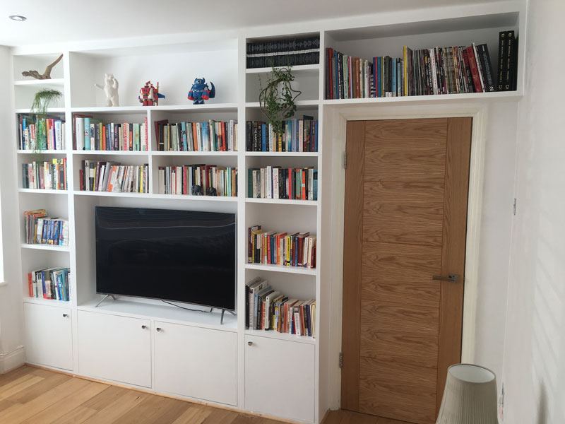 Fitted wall of shelves with cupboards below