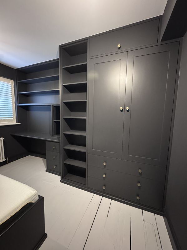 Wardrobe, shelving tower and desk fitted along one wall of a small bedroom