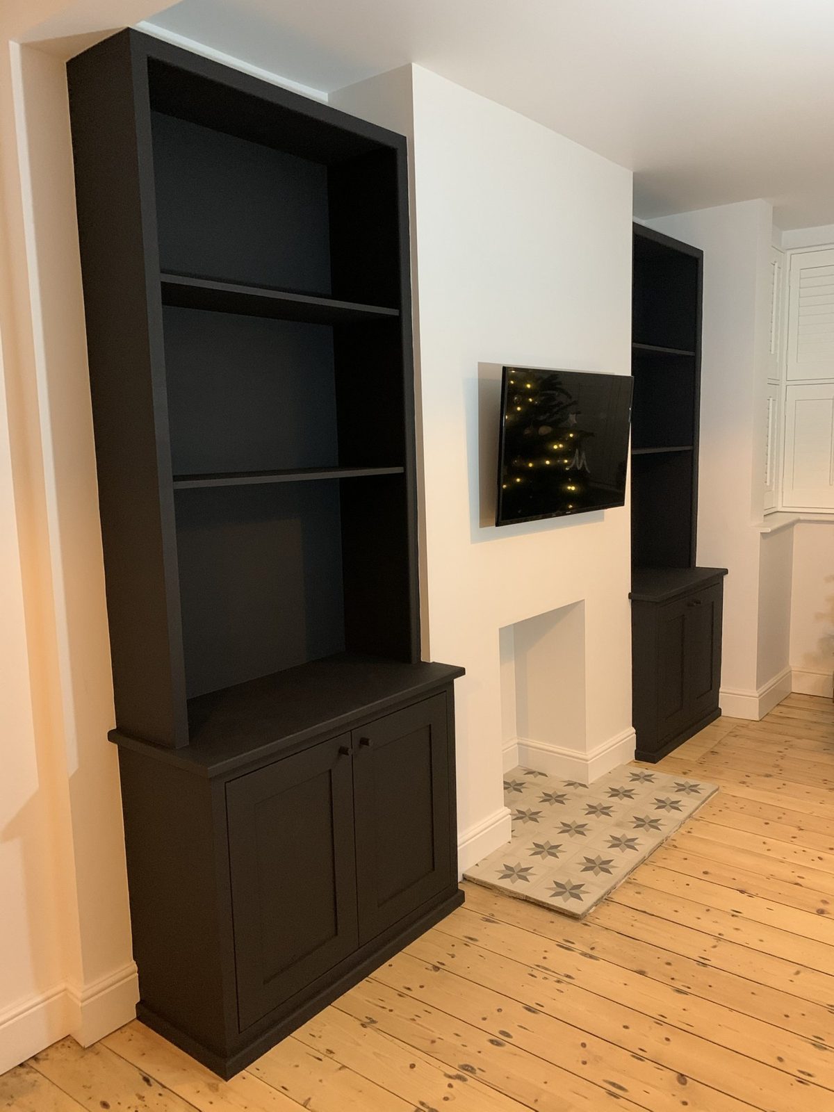 Matt black alcove cupboards and shelves either side of a chimney breast