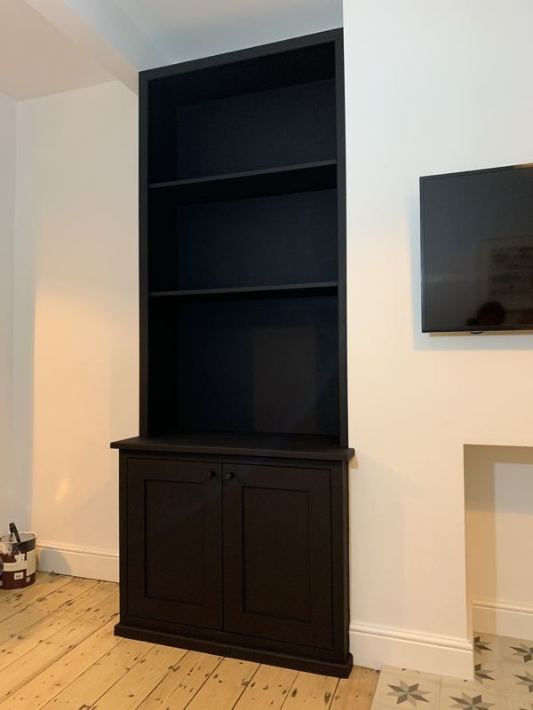 Tall matt black alcove shelves above a two-door cupboard
