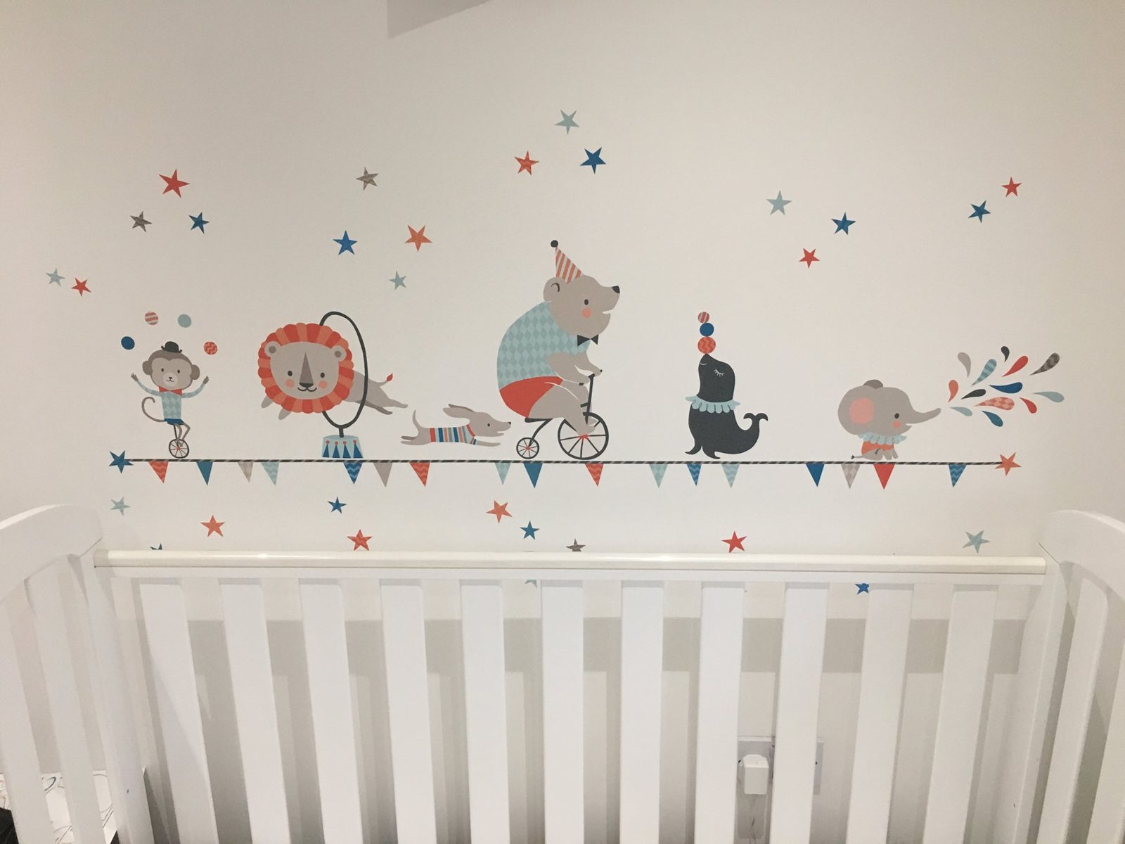 Circus animal wall stickers above a white cot