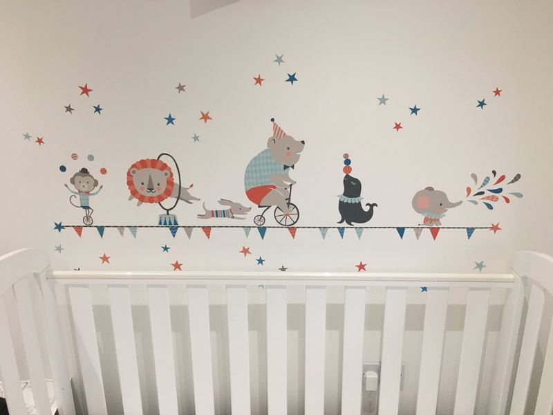 Circus animal wall stickers above a white cot