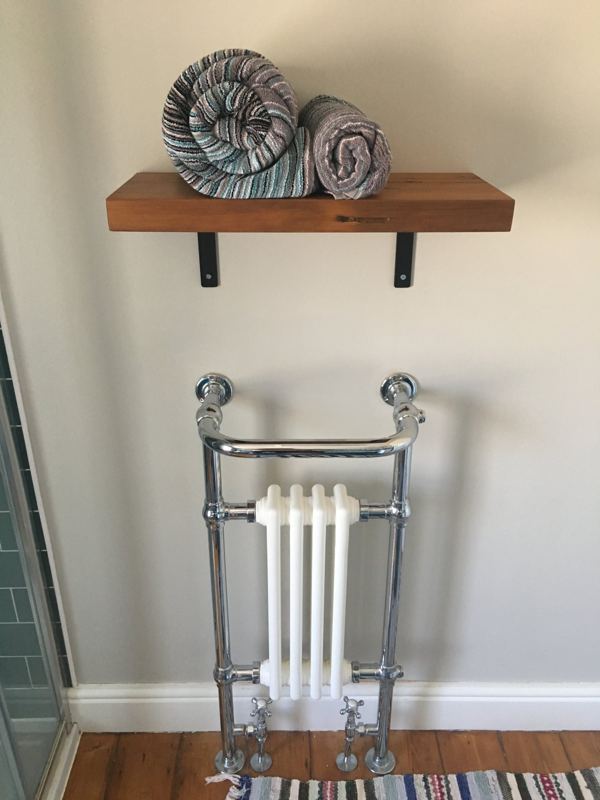 Chunky reclaimed wood shelf holding rolled towels